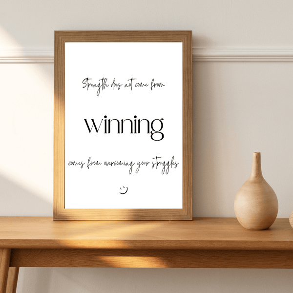 Front view of wall art featuring the quote 'Strength does not come from winning' in elegant typography of a living room mockup